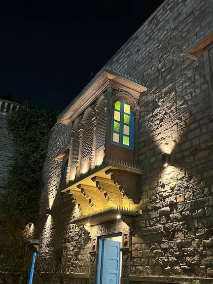 Another perspective of the beautiful Jodhpur architecture at night. The contrast between the rough stone, the smooth jharokha, and the colored glass window shows a masterful mix of materials and textures.