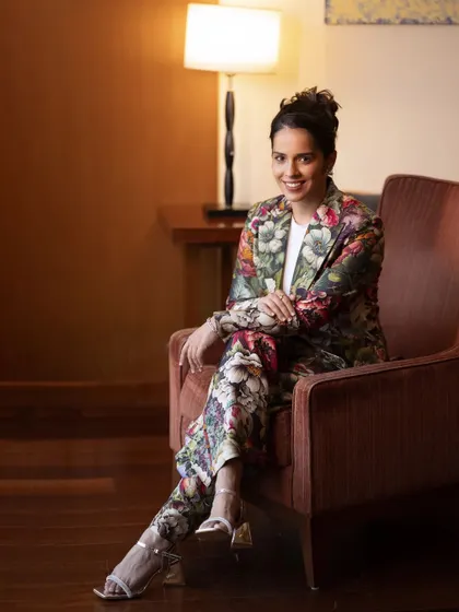 A full-length portrait of Saina Nehwal, showing her poised and relaxed in a comfortable setting. It’s a great example of a lifestyle portrait for a public figure.