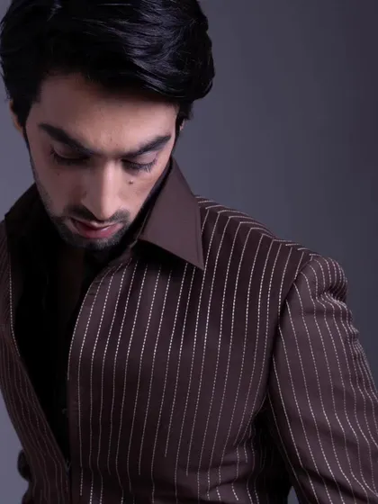 A close-up on the brown pinstripe suit, focusing on the texture and cut of the lapel. It's a timeless look that exudes confidence.