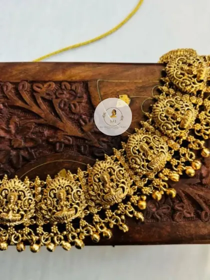 A close-up of a classic temple jewellery choker. The design features Goddess Lakshmi motifs across the necklace, finished with delicate golden beads for a timeless look.