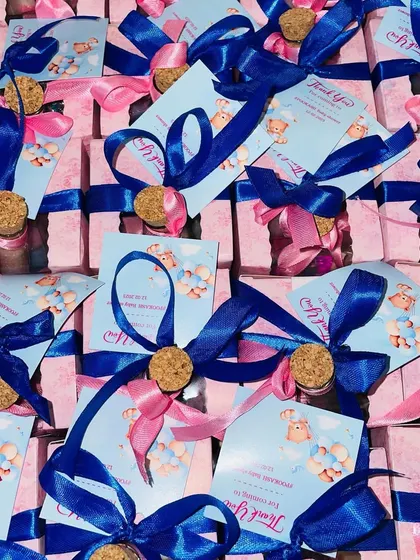 A large batch of our bottle-themed baby shower favors, with alternating pink and blue ribbons.