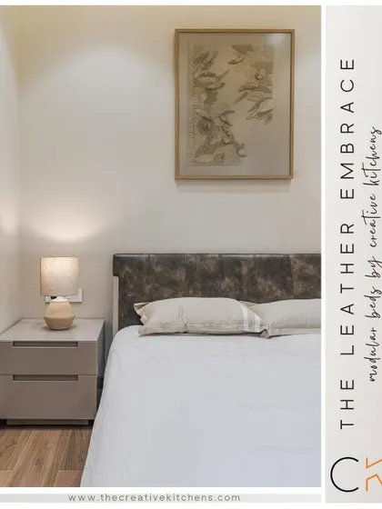 A close-up of the leather headboard and custom side table. The combination of textures, from the supple leather to the smooth finish of the furniture, adds depth and sophistication to the bedroom.