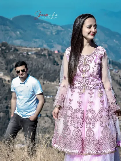 A pre-wedding shot with the bride-to-be in focus and her partner in the background. This composition creates a sense of depth and story against the mountain landscape.