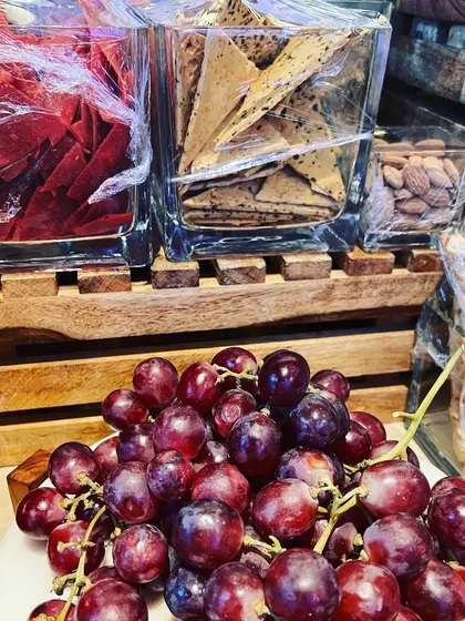 A rustic and charming grazing setup for a baby shower, featuring fresh grapes, assorted crackers, and nuts, ready for guests to enjoy.