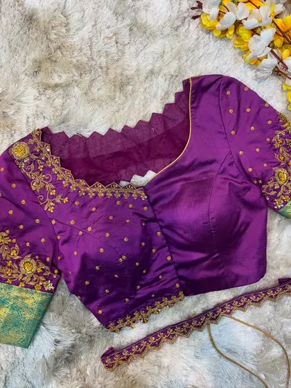 A purple blouse with a contrasting green Kanjeevaram silk border on the sleeves, embellished with gold butti and floral embroidery.