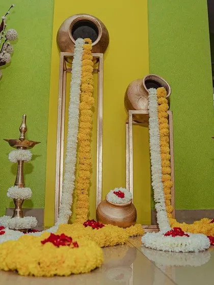 An indoor Haldi decor detail, where garlands of marigold and tuberose appear to flow out of brass pots, creating a beautiful and artistic installation.