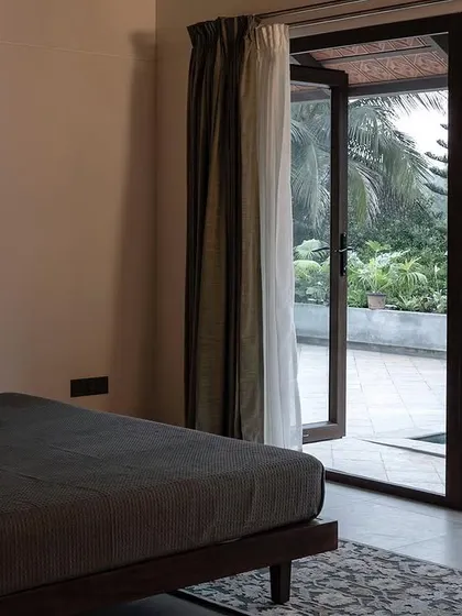 A simple, minimalist bedroom with a low bed and glass doors opening to the pool deck. The focus is entirely on the view, creating a serene space for rest.