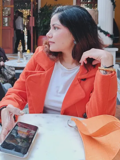 A profile view showing the clean lines of the orange coat and how it pairs effortlessly with a basic white top. It’s a testament to investing in classic pieces in bold, beautiful colors.