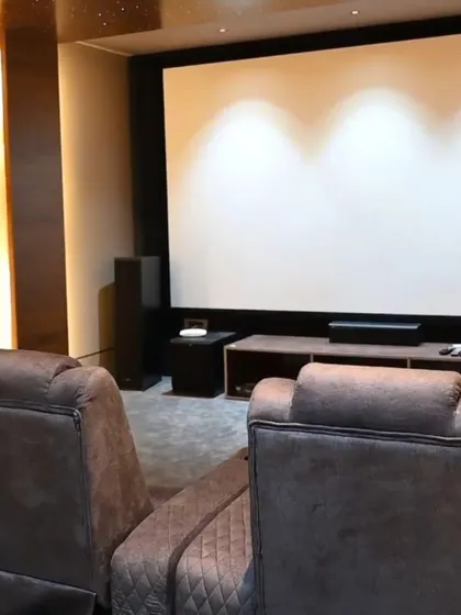 A view from the back of a dedicated home theater we completed, showing the large screen, surround sound speakers, and comfortable seating, all under automated control.