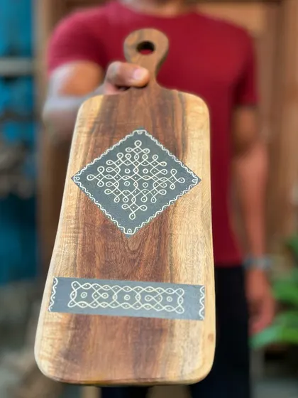 A wooden platter hand-painted with intricate rangoli patterns. These limited-edition pieces are perfect for adding a touch of traditional artistry to your home, either on a wall or a coffee table.