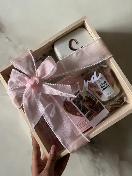 A beautifully assembled bridesmaid hamper in a wooden box, tied with a delicate pink ribbon. It's filled with personalized and luxurious items for your best girls.