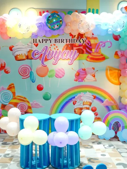 The full candy-themed stage setup, complete with a rainbow, clouds, and an array of sweet treats. This backdrop creates a vibrant and joyful atmosphere for the party.
