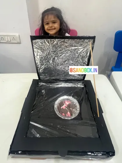 This little girl is all smiles with her completed solar cooker. She learned how reflective surfaces can concentrate sunlight to generate heat, enough to melt some marshmallows!