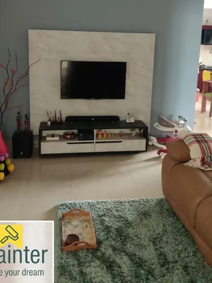 A living room with light blue-grey walls, creating a calm and contemporary atmosphere around the TV and entertainment unit.