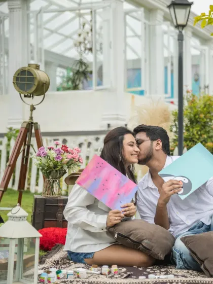 A sweet kiss during a creative picnic. This shot captures the fun of a painting date combined with the romance of a pre-wedding moment.
