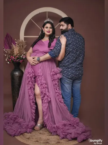 Another beautiful angle from the royal purple maternity shoot, showcasing the flowing gown and the elegant studio backdrop.