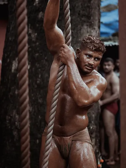 Wrestlers are seen using thick ropes for strength training, their muscles straining with the effort. These images highlight the rigorous physical conditioning that is part of the daily routine.