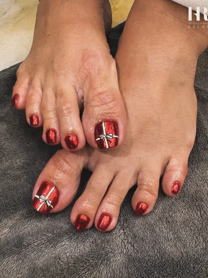 Don't forget your toes. We gave this client a festive pedicure with a stunning metallic red polish and a cute gift bow design on the big toe to match the holiday mood.