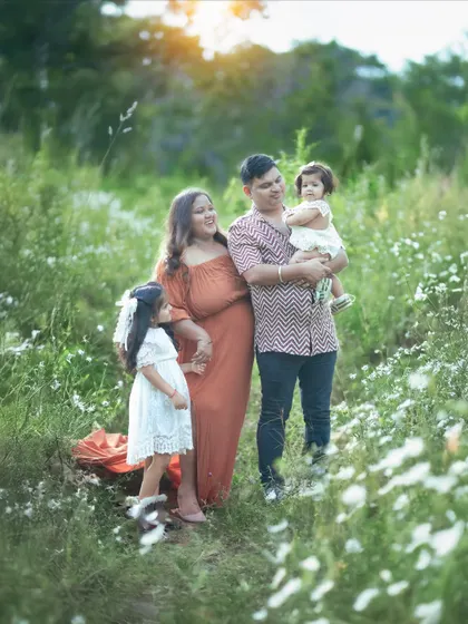 A candid moment of the family interacting in the wildflower field. The warm sunset light makes everything glow.