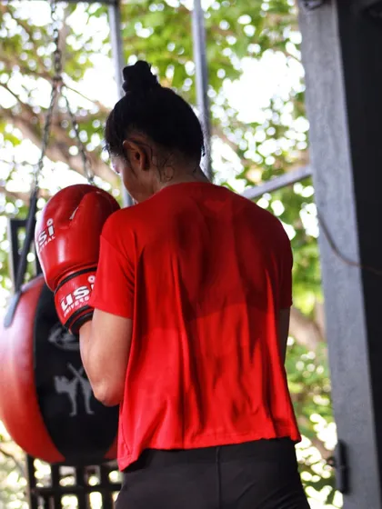 A shot from behind a female boxer working the slip bag, showing her focused posture.