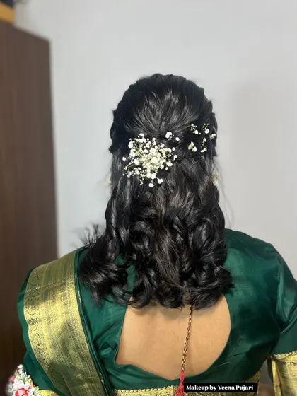 A delicate and pretty hairstyle for a party or pre-wedding event. The soft curls are gathered at the back and decorated with baby's breath for a romantic touch.