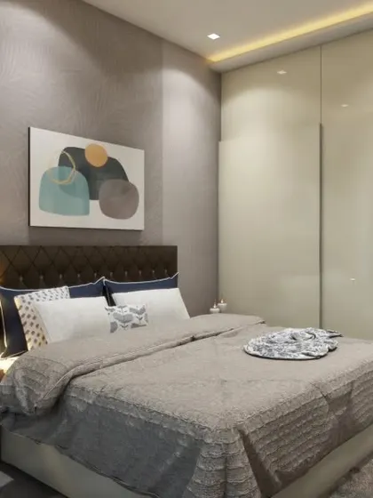 This bedroom features a tufted headboard, a stylish art piece, and a sleek vanity corner with a mirror. The glossy finish on the wardrobe doors reflects light and makes the room feel brighter.