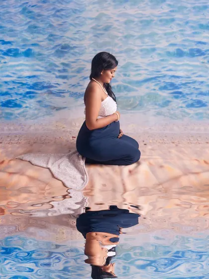 A creative and serene maternity photo with a "mermaid" theme. The makeup is natural and beachy, enhancing her glow for this unique and beautiful concept shoot.