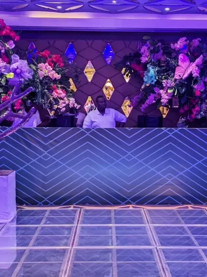 The DJ booth was framed by an explosion of colorful flowers and a modern, geometric-patterned console, ensuring the music hub was as visually exciting as the dance floor.