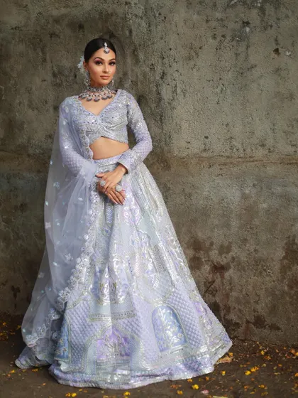 A model posing against a rustic wall in the lavender lehenga, showing how the outfit stands out in any setting.