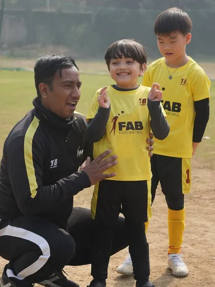 A coach celebrating with two young players. We prioritize holistic development, nurturing both athletic skills and personal growth.