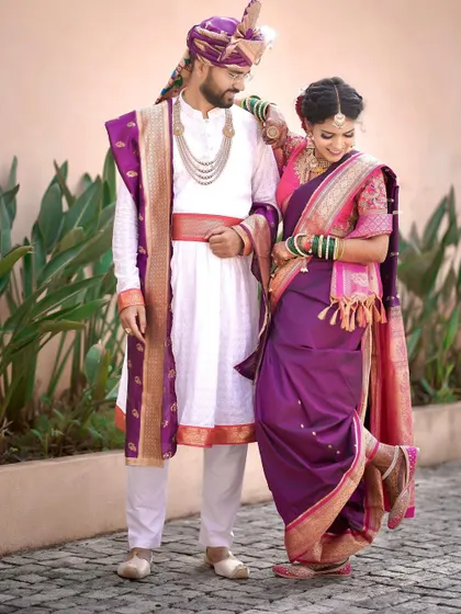 A playful and charming pose. The bride kicks up her heel, showing off her traditional footwear, while leaning on her groom, adding a touch of fun to their wedding portraits.