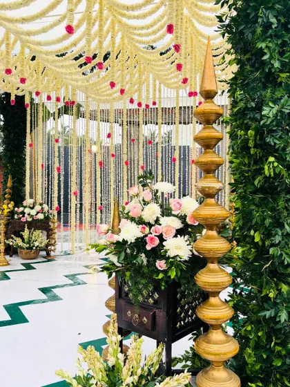 A detailed view of the corner of our green mandap, showing the traditional tiered brass lamp and floral arrangements that complete the look.