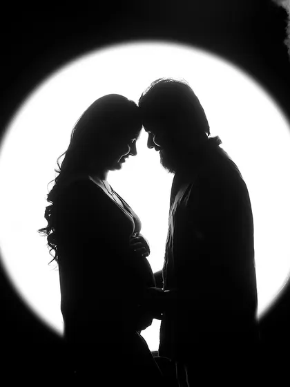 A dramatic silhouette of a couple against a circular light, resembling a full moon. This artistic black and white photo creates a powerful and symbolic image of their connection.