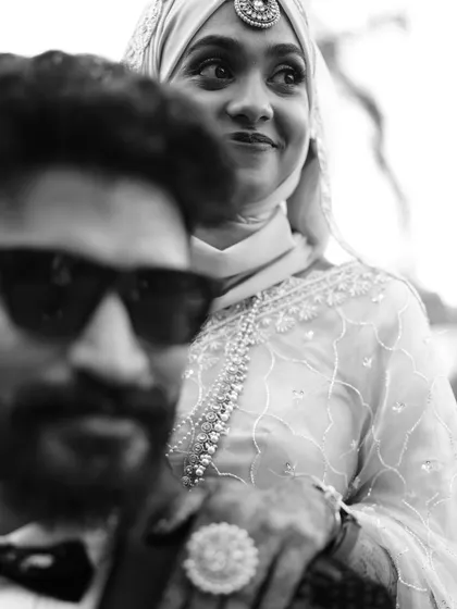 A creative black and white shot with the groom in the foreground and the bride looking on, creating a cool, artistic vibe.