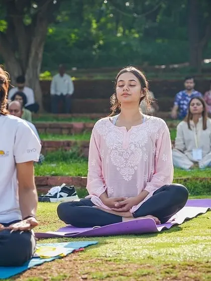 People of all ages meditating together in a park-like setting. Our programs are inclusive and demonstrate that the path to inner peace through yoga and meditation is open to everyone.
