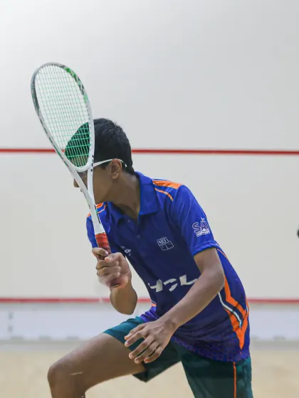 A close-up action shot of squash champion Aryaman Singh, demonstrating the focus and technique that led him to an Asian Championship medal.