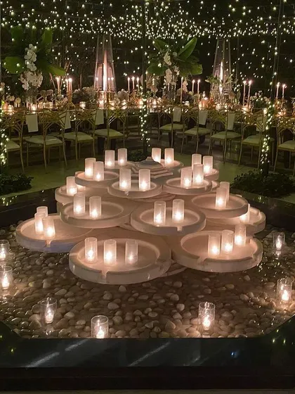 A creative and beautiful installation for a candlelit event. A central water feature is transformed with a multi-tiered candle display, creating a stunning focal point that reflects the light and adds to the magical atmosphere.