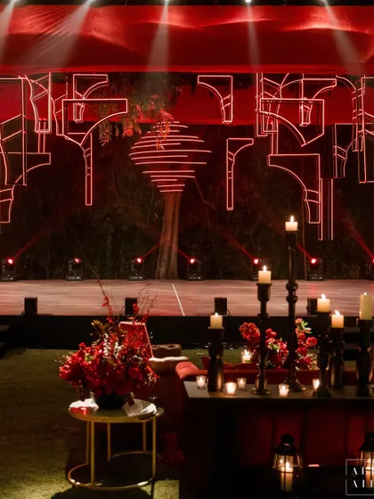 The modern, geometric stage backdrop at the 'Laal Bagh' reception, illuminated in red. This design element was inspired by the old-world charm and ruins of ancient Indian forts.