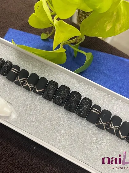 For those who love a dark and dramatic look, this black press-on set is perfect. It features a mix of matte black, textured glitter, and sharp silver line art for an edgy vibe.