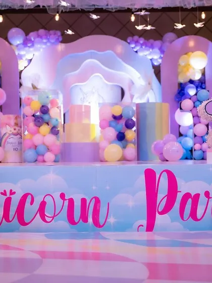 The front of the unicorn party stage, with custom lettering and colorful props.