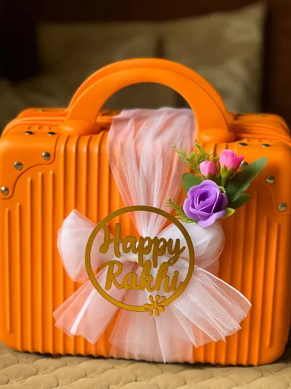Another beautifully decorated suitcase hamper for Rakhi, this one with a gold "Happy Rakhi" tag and delicate floral accents.