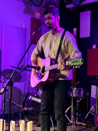 A musician performing a solo acoustic set. This image shows our standard setup with professional sound equipment, ensuring every note is heard clearly.