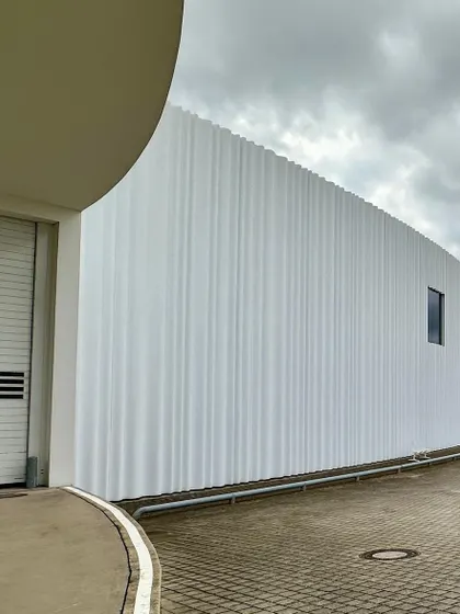 The curved, opaque wall of the SANAA building creates a sense of mystery and minimalist beauty.