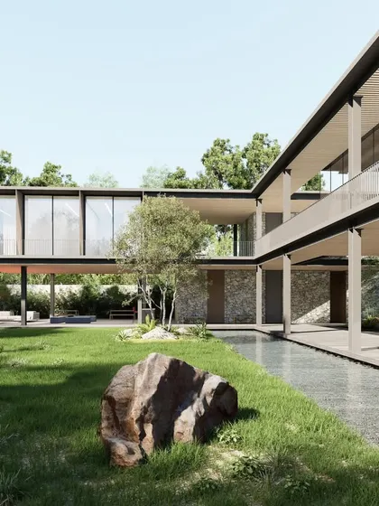 The design of this clubhouse uses a combination of stone, wood, and steel to create a warm yet modern aesthetic. The building is broken into smaller volumes connected by open decks and covered walkways, all oriented towards the central lawn and water feature.