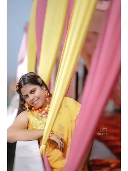 A playful peek through colourful curtains. A lovely, candid-style portrait of the bride Urvashi at her Haldi ceremony.