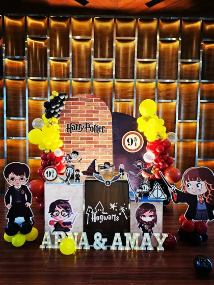 This Harry Potter theme for Arna and Amay's party features a brick wall backdrop leading to Platform 9 3/4. The setup is complete with character cutouts, house banners, and balloon arches in Hogwarts colors.