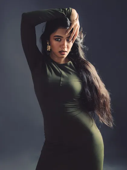 A powerful and slightly mysterious pose. The hand gesture draws attention directly to the model's expressive eyes.
