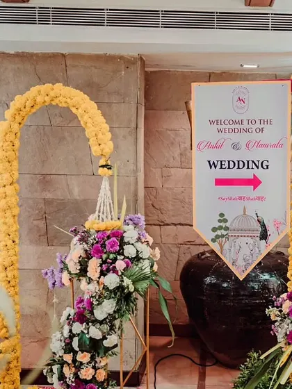 A custom welcome sign for the wedding of Shakil and Urmila. The sign is decorated with marigold flowers, matching the traditional theme of the event entrance.