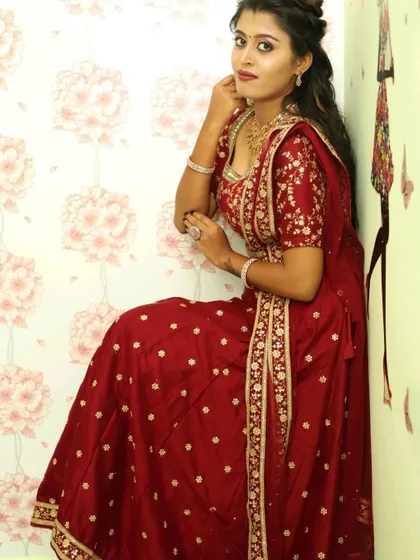 A seated pose in the maroon lehenga, showing the flow of the skirt and the detailed border on the dupatta.