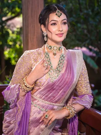 When radiance meets tradition. This look features a unique lilac drape with emerald jewels, complemented by a dewy makeup finish that enhances her natural glow.
